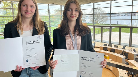 Zwei Schülerinnen mit Urkunde stehen auf der Tribüne im Plenarsaal des Kieler Landeshauses. © NDR Foto: Friederike Hoppe