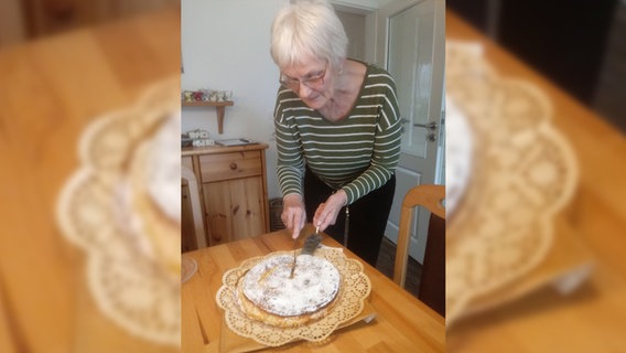 Eine Frau schneidet einen selbst gebackenen Kuchen an. © NDR Foto: Peter Bartelt
