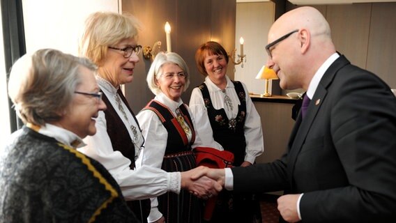 Ministerpräsident Torsten Albig begrüßt norwegische Besucherinnen in Landestrachten © dpa - Bildfunk Foto: Carsten Rehder