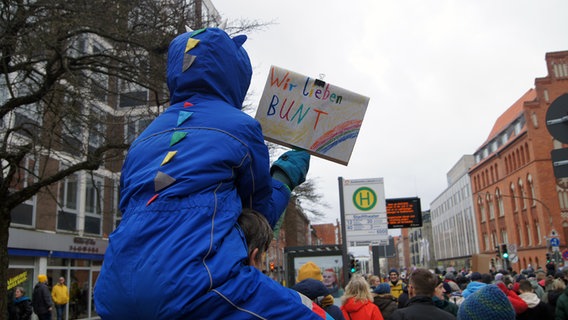 Ein Kind sitzt auf den Schultern seines Vaters und hält ein Schild mit der Aufschrift "Wir lieben BUNT" hoch. © NDR Foto: Astrid Wulf