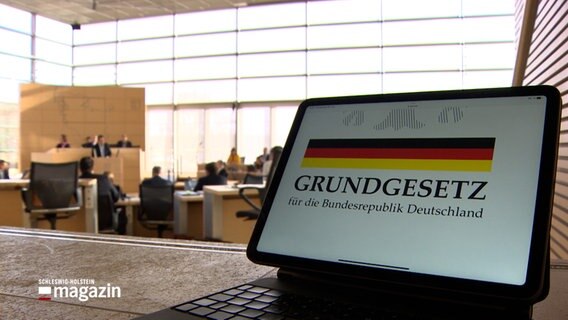 Im Landtag ist ein Laptop aufgeklappt auf dem "Grundgesetz" zu lesen ist. © NDR 