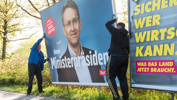 Mitarbeiter einer Werbefirma bauen ein Wahlplakat von Daniel Günther (CDU), Ministerpräsident von Schleswig Holstein, zur Landtagswahl Schleswig-Holstein ab.  Foto: Daniel Bockwoldt
