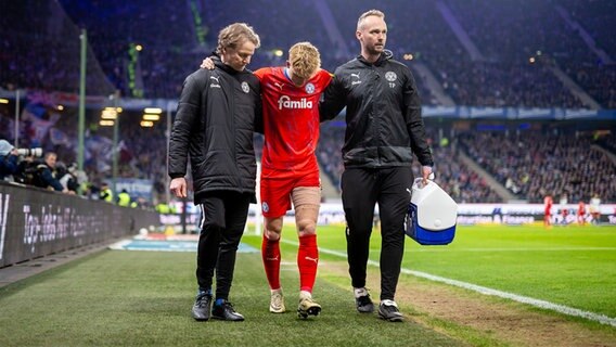Holstein Kiel Spieler Finn Porath wird im Hamburger Volksparkstadion mit einer Verletzung von zwei Männern vom Platz begleitet. © picture alliance / xim.gs Foto: Philipp Szyza