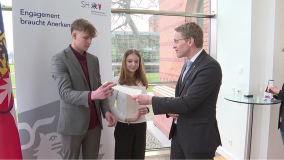 Zwei Jugendlichen erhalten eine Rettungsmedaille von Ministerpräsident Daniel Günther überreicht. © NDR 