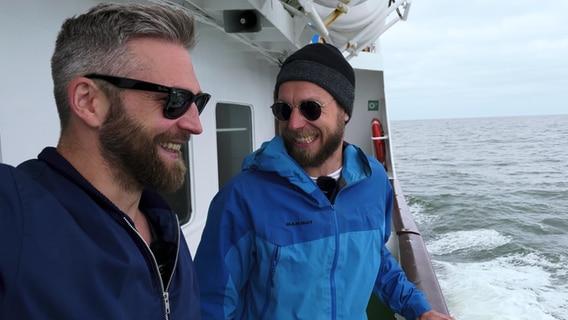 Philipp Jess (Links) und Jonas Drescher (Rechts) blicken über die Bordkante des Boots © NDR Foto: Screenshots