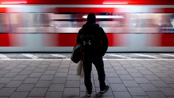 Eine Person steht auf einem Bahnsteig und eine S-Bahn fährt vorbei. © picture alliance/dpa Foto: Sven Hoppe