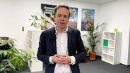Rasmus Andresen (B90/Die Grünen) lächelt in einem Büroraum in die Kamera. © NDR 