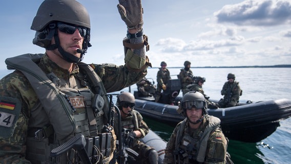 Ein Mann des Seebataillon sitzt mit anderen Soldaten in einem Schlauchboot und gibt ein Handzeichen. © Presse- und Informationszentrum Marine Foto: Presse- und Informationszentrum Marine