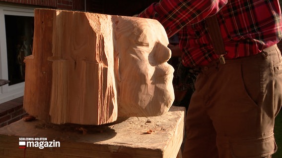 Eine Holzskulpture mit einem Gesicht steht auf einem Sockel © NDR 