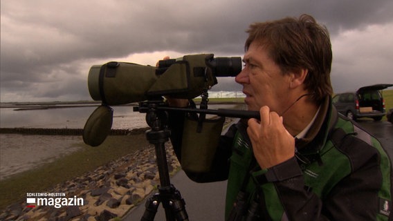 Ein Mann blickt durch ein Fernglas, es ist Martin Kühn, Nationalparkranger im Wattenmeer bei einer Vogelzählung. © NDR Foto: NDR Screenshots