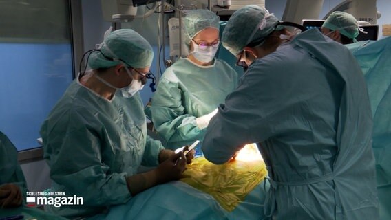 Medizinisches Personal steht während einer Operation in einem OP-Raum © NDR Foto: NDR Screenshot