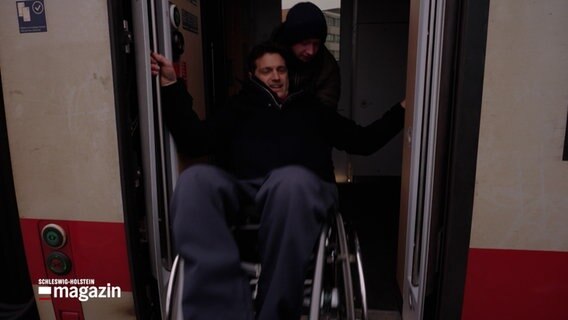 Ein Mann im Rollstuhl wird von einem anderen Fahrgast in einen Zug gezogen. © NDR Foto: NDR Screenshot