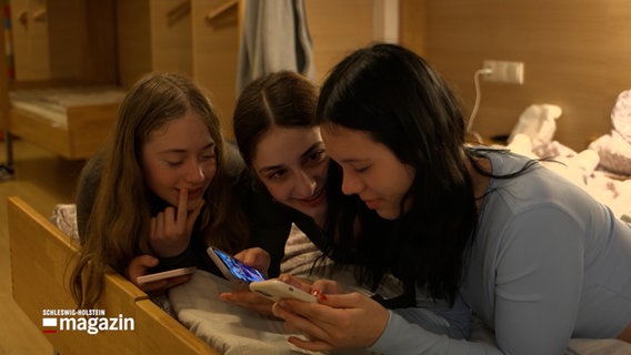 Mehrere Mädchen liegen auf einem Bett und betrachten ihre Smartphonebildschirme © NDR Foto: NDR Screenshot