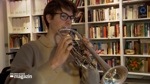 Ein Trompetenspieler spielt vor einem Bücherregal © NDR Foto: NDR Screenshot