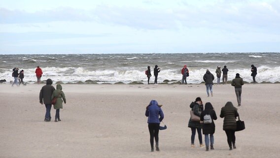 Besucher sind bei stürmischem Wetter am Strand von Travemünde unterwegs. © dpa-Bildfunk Foto: Bodo Marks