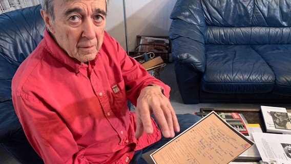 Josef Salomonovic sitzend auf einem Sessel mit einem Dokument in der Hand. © NDR Foto: Corinna Below