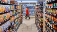 Eine Frau geht zwischen Supermarkt-Regalen entlang. © picture alliance Foto: Carsten Milbret