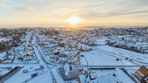 Eine Drohenenaufnahme zeigt eine Ortschaft auf Sylt von oben bei Sonnenaufgang. © Studio Sylt Foto: Georg Heimberger