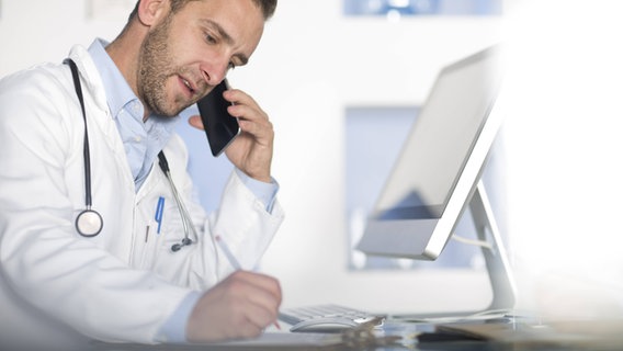 Ein Arzt macht Notizen, während er telefoniert. © Imago/Westend61 Foto: Westend61