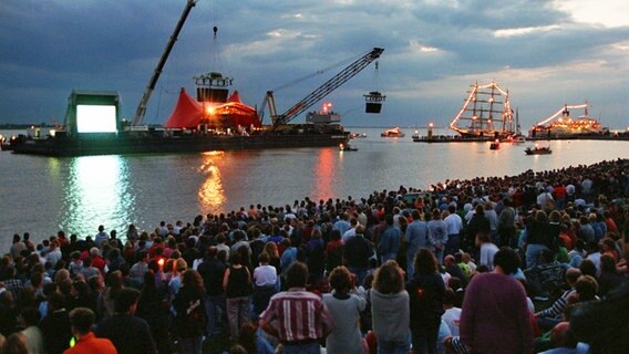 Rund 20.000 Zuschauer warten am 24. August 1996 am Weserdeich in Bremerhaven vor einer schwimmenden Bühne auf den Auftritt der Rockgruppe Scorpions. © picture-alliance / dpa 