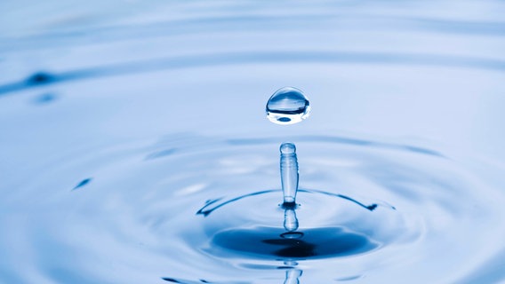 Ein einzelner Wassertropfen spritzt von einer Wasserfläche. © imago images Foto: Design Pics