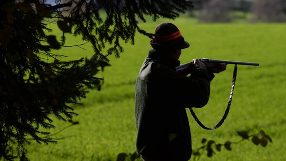 Ein Jäger steht mit einem Gewehr schussbereit am Waldrand. © picture alliance / dpa Foto: Felix Kästle