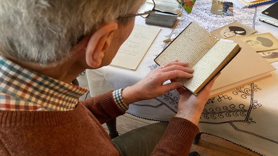 Ein älterer Herr liest in einem Tagebuch. © NDR Foto: Philip Schroeder