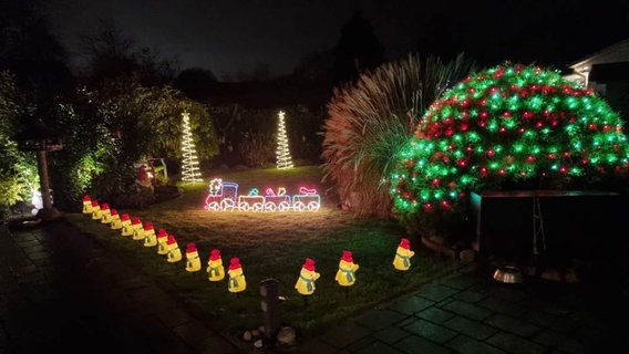 Bunt leuchtender Garten von Olaf Harder in Wedel - mit dekorierten Sträuchern und Weihnachtsmann-Gespann, umgeben von gelb erleuchteten Weihnachtsmännern © Privat Foto: NDR 2 Hörer Olaf Harder