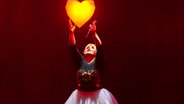 Schlagersängerin Maite Kelly greift auf der Bühne nach einem leuchtenden Herzen, Pressefoto © Chris Heidrich / Semmel Concerts Entertainment Foto: Chris Heidrich