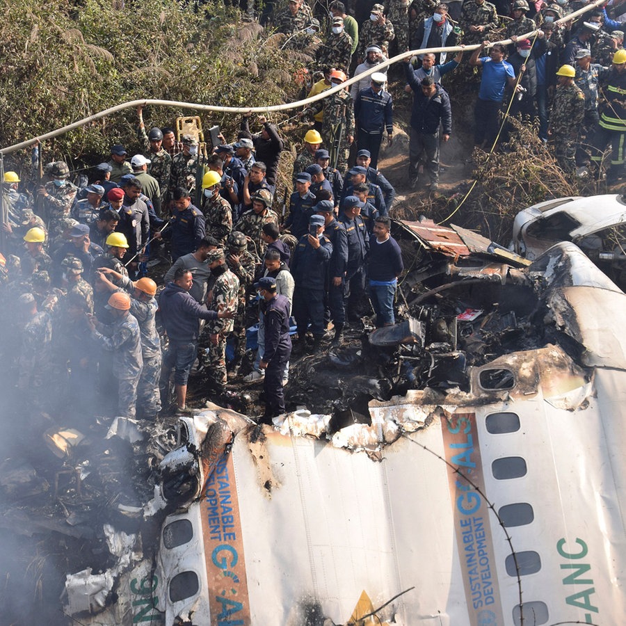 Nepalesische Rettungskräfte arbeiten an dem Wrack eines abgestürzten Passagierflugzeugs in Pokhara. © AP/dpa Foto: Krishna Mani Baral