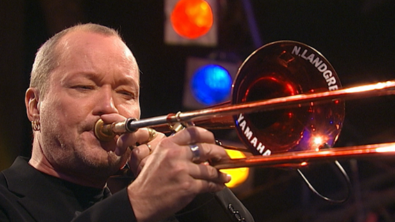 Screenshot: Posaunist Nils Landgren spielt mit der NDR Bigband und Jazz-Schlagzeuger Wolfgang Haffner im Jahr 2007 auf der JazzBaltica. © NDR Bigband 