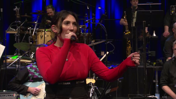 Screenshot: Salomea am Mikrofon beim Konzert mit der NDR Bigband und TOYTOY auf Kampnagel. © NDR Bigband Foto: Screenshot