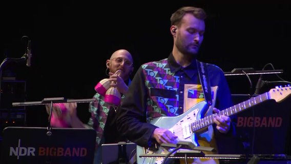Screenshot: Alex Eckert von der Band TOYTOY spielt Gitarre beim Konzert mit der NDR Bigband im Rolf-Liebermann-Studio. © NDR Bigband Foto: Screenshot