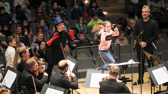 Szene eines Familienkonzerts in der Elbphiharmonie: Ein Mädchen springt auf das Dirigentenpult. © NDR Foto: Marcus Krüger