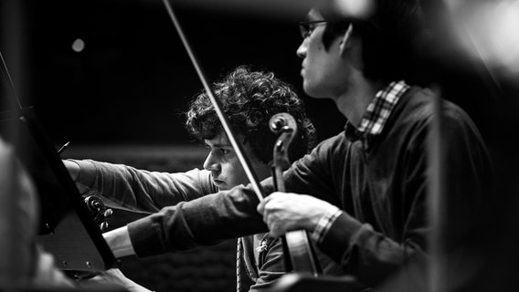 Probenszene: Die Violinisten Julius Beck und Alexander Sprung vom NDR Elbphilharmonie Orchester in einer Probe (Schwarz-weiß-Bild) © NDR Foto: Peter Hundert