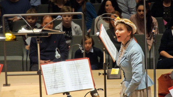 NDR Redakteurin Christina Dean steht in historischem Kostüm auf der Bühne beim Konzert des NDR Jugendsinfonieorchesters. © NDR Foto: Mairena Torres