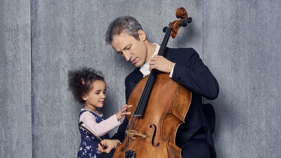 Ein Mädchen und der Cellist der NDR Radiophilharmonie begutachten ein Cello © NDR Foto: Micha Neugebauer