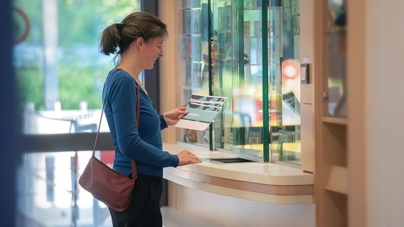 Eine junge Frau an der Kasse des Ticketshops im NDR Landesfunkhaus Hannover mit Konzertkarten in der Hand © NDR Foto: Micha Neugebauer