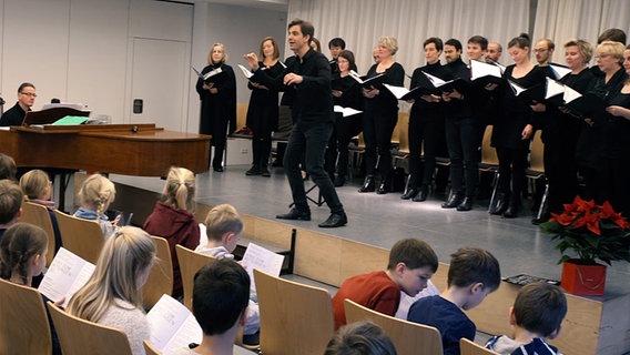 Screenshot: Hannes Reich und der NDR Chor beim "Kino zum Mitsingen" in einer Schweriner Grundschule. © NDR Foto: Screenshot