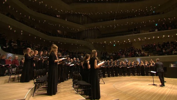 Screenshot: Klaas Stok dirigiert beim Mitsingkonzert SINGING!2019 das NDR Vokalensemble und 1056 Gastsängerinnen und Gastsänger sowie Musikstudierende. © NDR Vokalensemble Foto: Screenshot