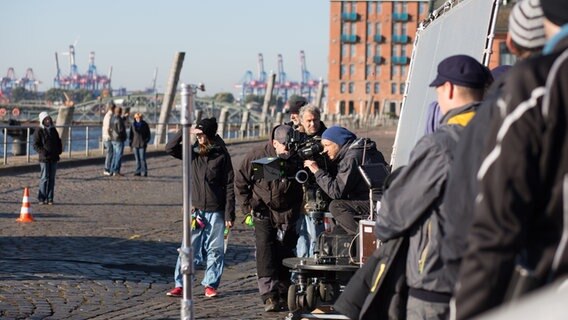 Das Team steht um den Kameramann am Hafen. © NDR Foto: Claudia Timmann