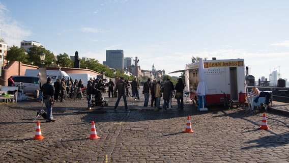 Das Filmteam steht am Hafen vor dem Imbisswagen. © NDR Foto: Claudia Timmann