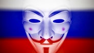 Eine Guy Fawkes Maske vor einer russischen Flagge. © picture alliance / NurPhoto | Jakub Porzycki 
