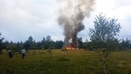 Auf diesem Videobild steigen Rauch und Flammen aus einem abgestürzten Privatjet in der Nähe des Dorfes Kuschenkino in der Region Twer. © dpa-Bildfunk Foto: Uncredited