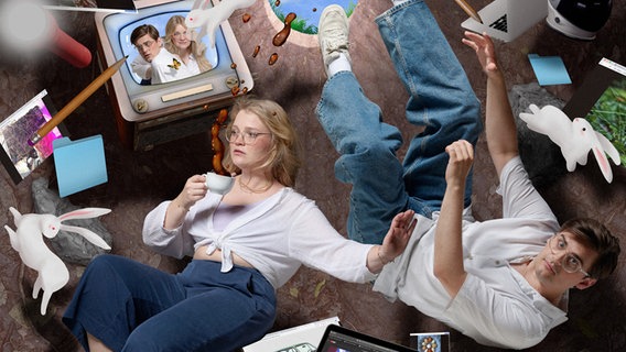 Mann und Frau liegen zwischen Laptops und Monitoren. © NDR 