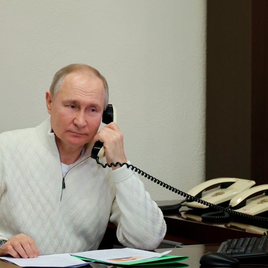 Russlands Präsident Vladimir Putin am Telefon. Hinter ihm zwei weiße ältere Telefone. © picture alliance / ASSOCIATED PRESS | Mikhail Klimentyev 