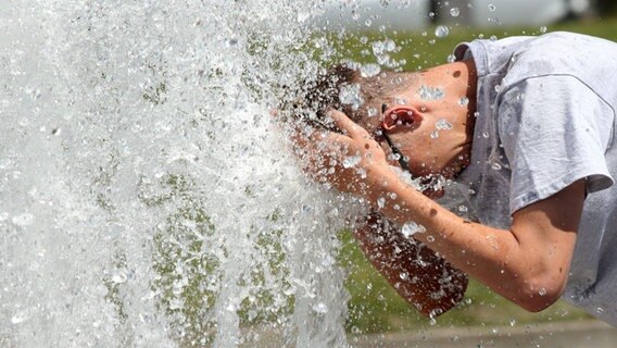 Ein Mann erfrischt sich am Wasser eines Brunnens © picture alliance/dpa | Wolfgang Kumm Foto: Wolfgang Kumm