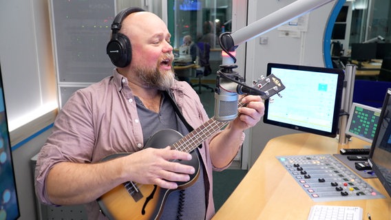 Stefan Kuna im Hörfunkstudio mit einer Ukulele. © Screenshot 