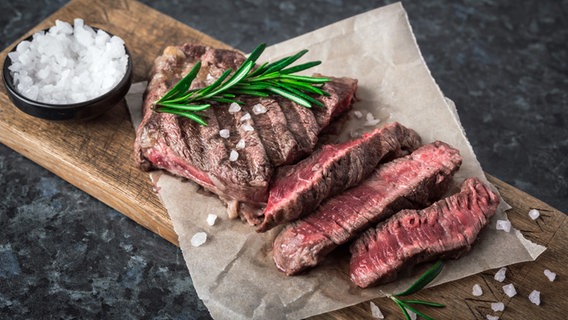 Saftiges Ribeyesteak in Scheiben aufgeshnitten auf einem Holzbrett. © Picture Alliance 