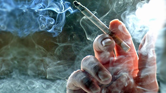 Eine Hand hält eine qualmende Zigarette. © dpa 